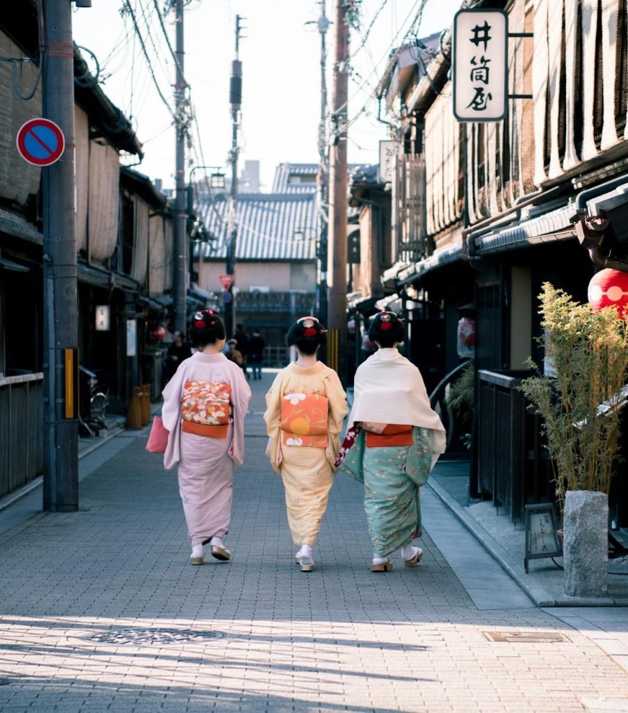 three woman wearing traditional dresses walking on street